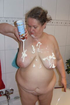Big mama playing with whipped cream in the tub